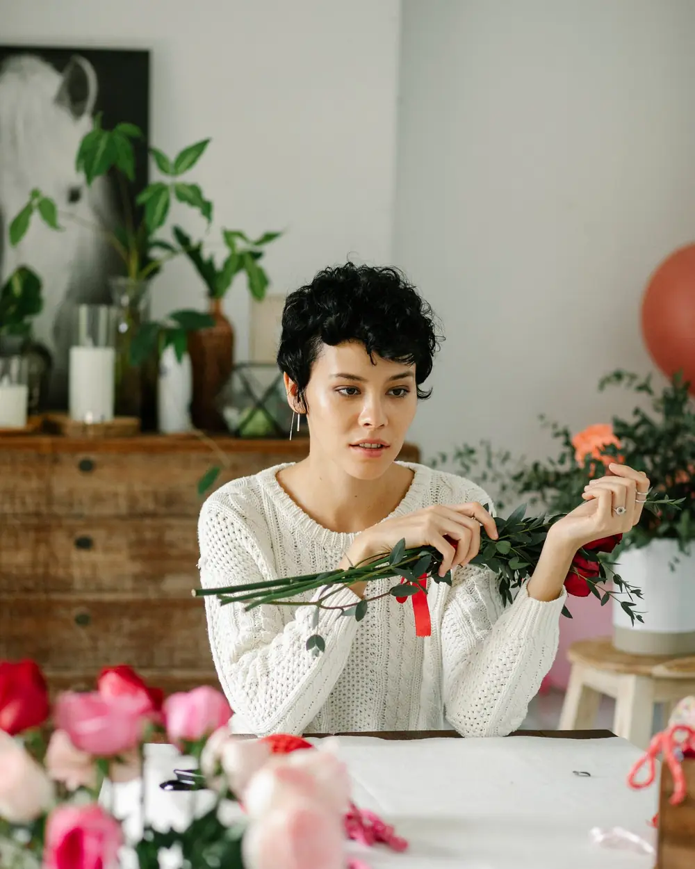 Symbolbild: Floristin bindet in einem hellen Atelier Zweige zu einem Strauß.