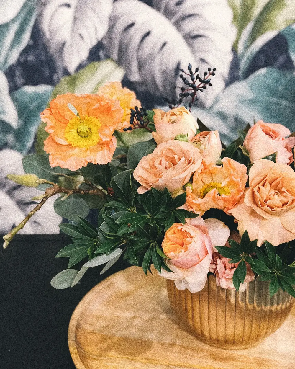Herbstlicher Strauß aus Mohnblüten und Rosen in einer Messingvase.